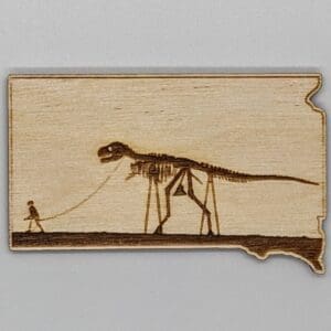 Custom wood magnet in the shape of South Dakota depicting a skeleton man walking a skeleton dinosaur