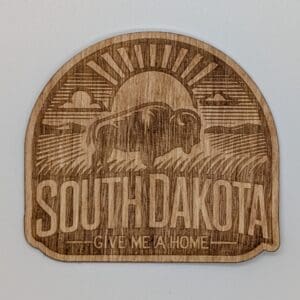 Wood sticker showing a buffalow with a sun filled praire vista with South Dakota give me a home text