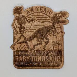 Wooden sticker depicting a skeleton man walking a skeleton dinosaur with the text bringing home a baby dinosaur Midland, South Dakota