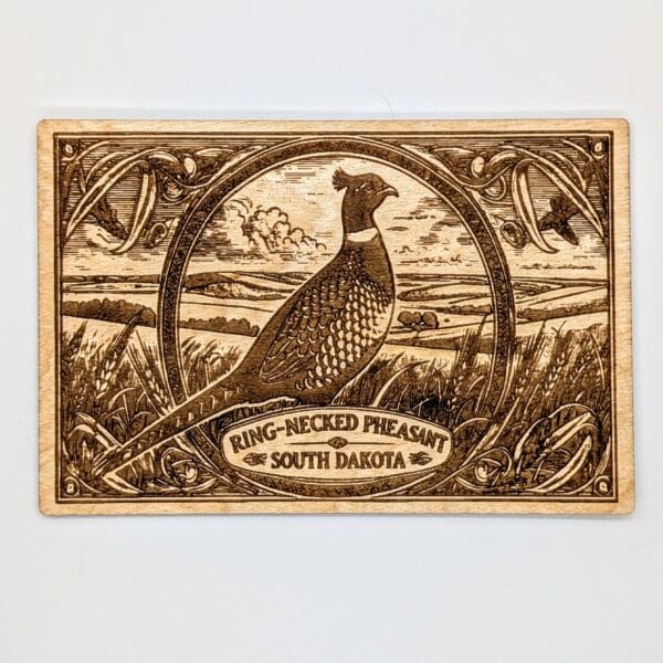 Wood carved postcard showing a ring-necked pheasant and South Dakota vista