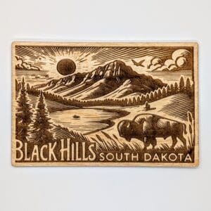 Wood carved postcard depicting Black Hills South Dakota with the sun showing over the hills with forest and a buffalo